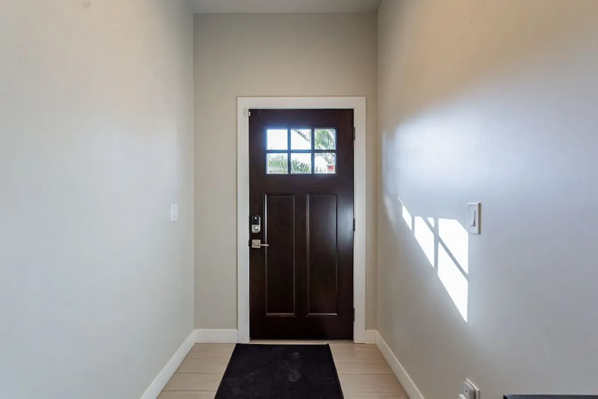 This image highlights the home's entryway, focusing on the front door and stylish flooring. The scene conveys the sense of transition from the vibrant neighborhood streets into the welcoming retreat of PHX Retreat.